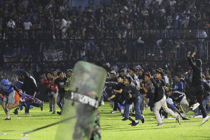 Aficionados al fútbol corren durante una serie de enfrentamientos en Indonesia