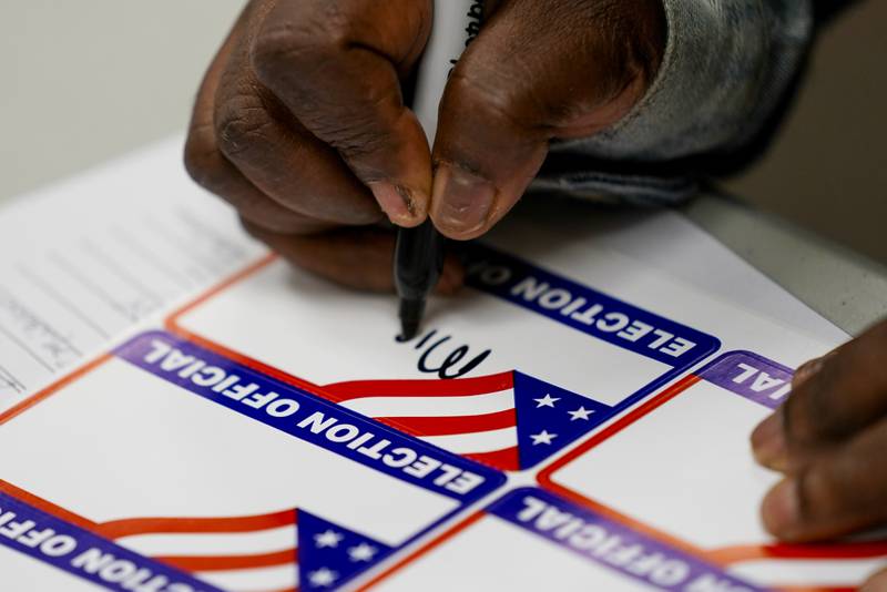 Un trabajador electoral firma durante una clase para trabajadores electorales de Milwaukee el sábado 22 de octubre de 2022, en Milwaukee. (AP Photo/Morry Gash)