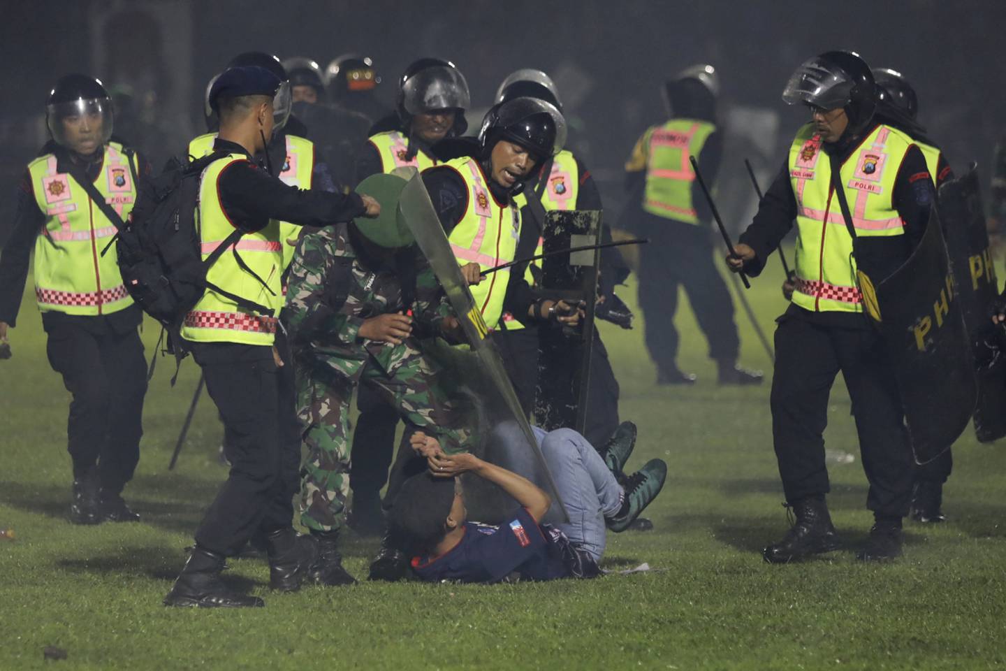 Agentes de seguridad detienen a un aficionado durante una serie de trifulcas en un partido de fútbol en Indonesia