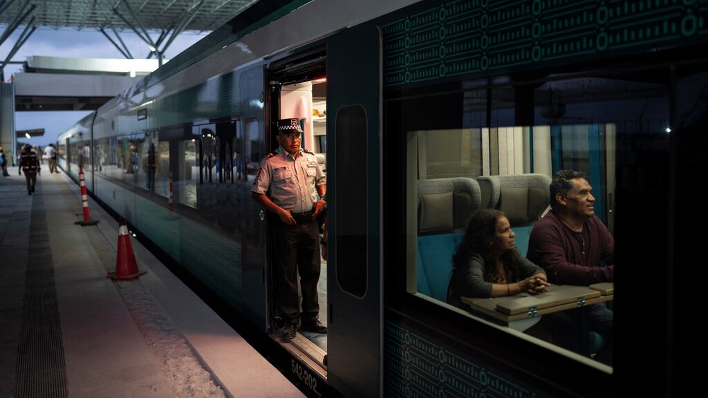 Un trabajador del Tren Maya espera que los pasajeros aborden el vagón en Cancún, México.