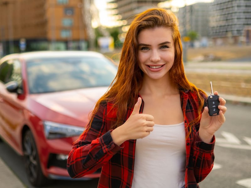 Mujer joven sosteniendo las llaves de su auto, representando el momento de comprar tu primer auto
