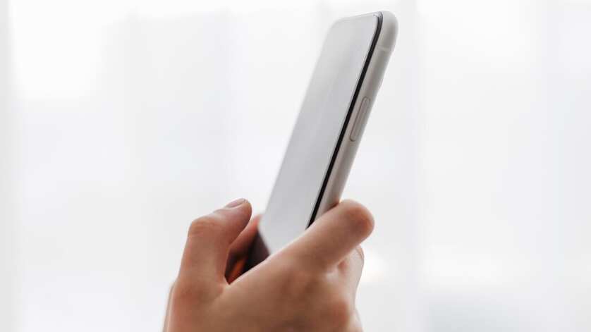 Persona de vista lateral sosteniendo un teléfono móvil