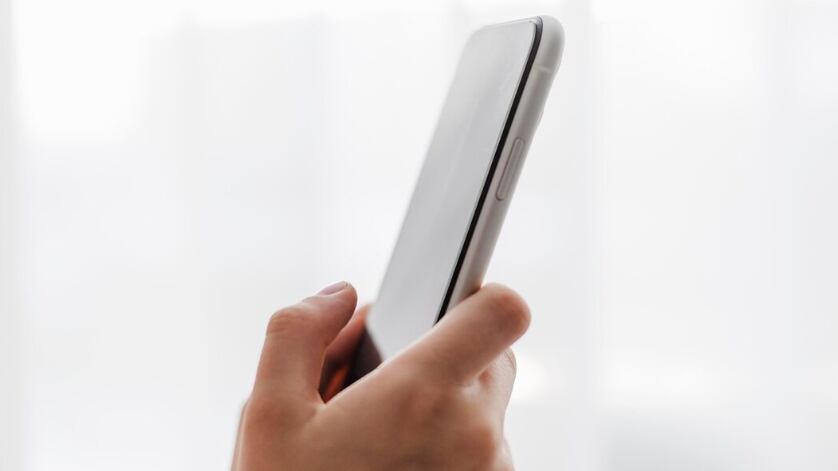 Persona de vista lateral sosteniendo un teléfono móvil