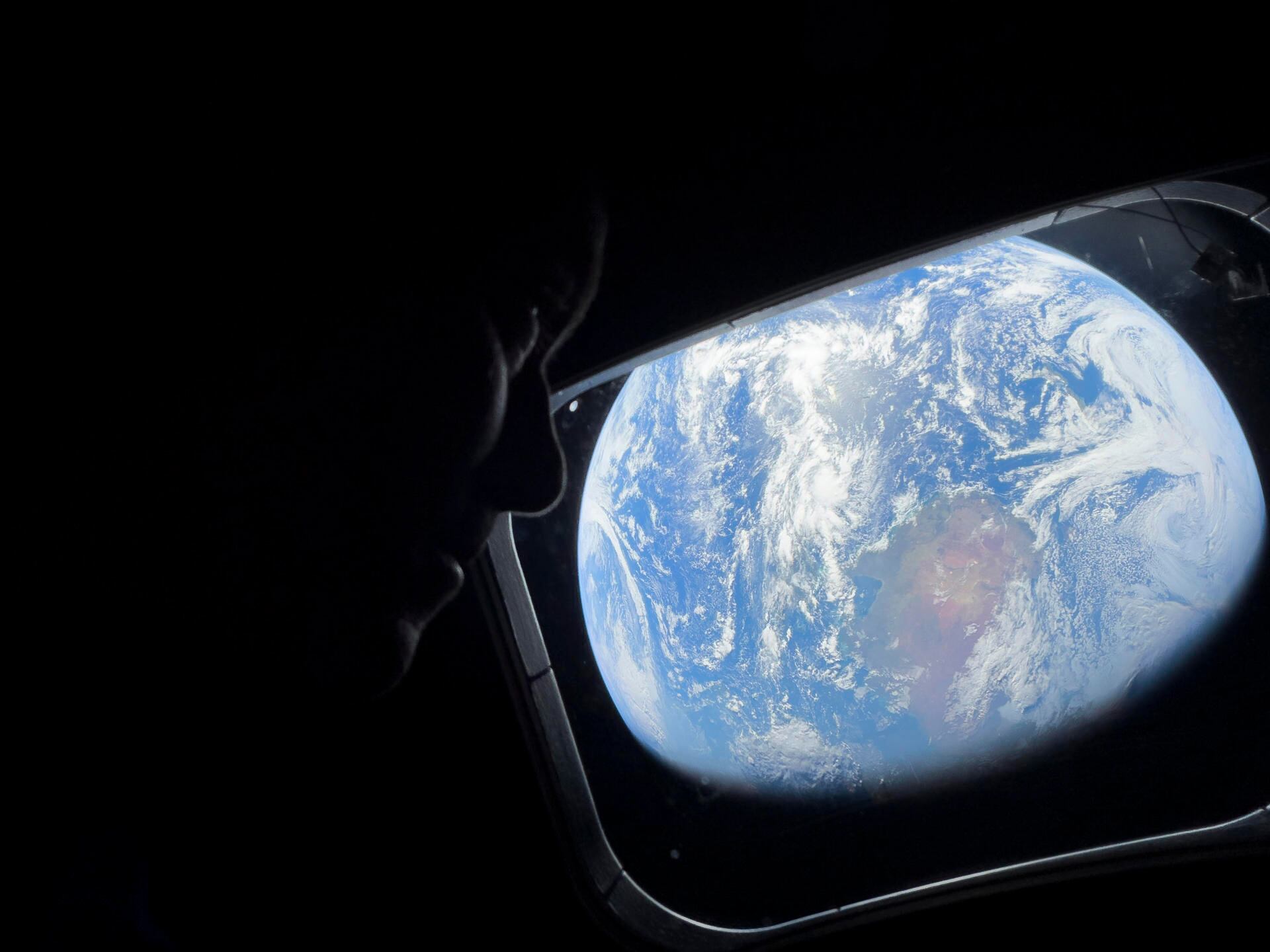 El comandante Reid Wiseman observa la Tierra mientras continúan adentrándose en el espacio hacia la Luna.