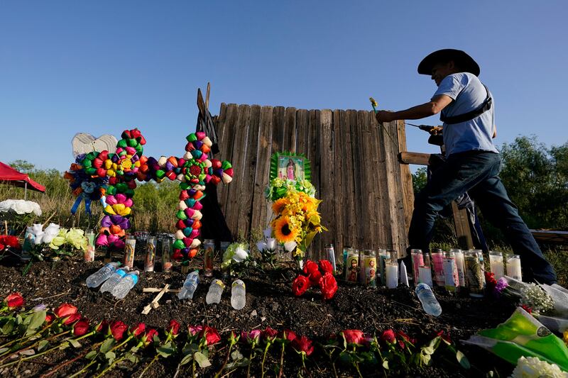 Roberto Marquez, de Dallas, coloca una flor el 29 de junio de 2022, en un altar instalado donde las autoridades estadounidenses encontraron a decenas de personas muertas en un camión de carga, en San Antonio, Texas. (AP Foto/Eric Gay