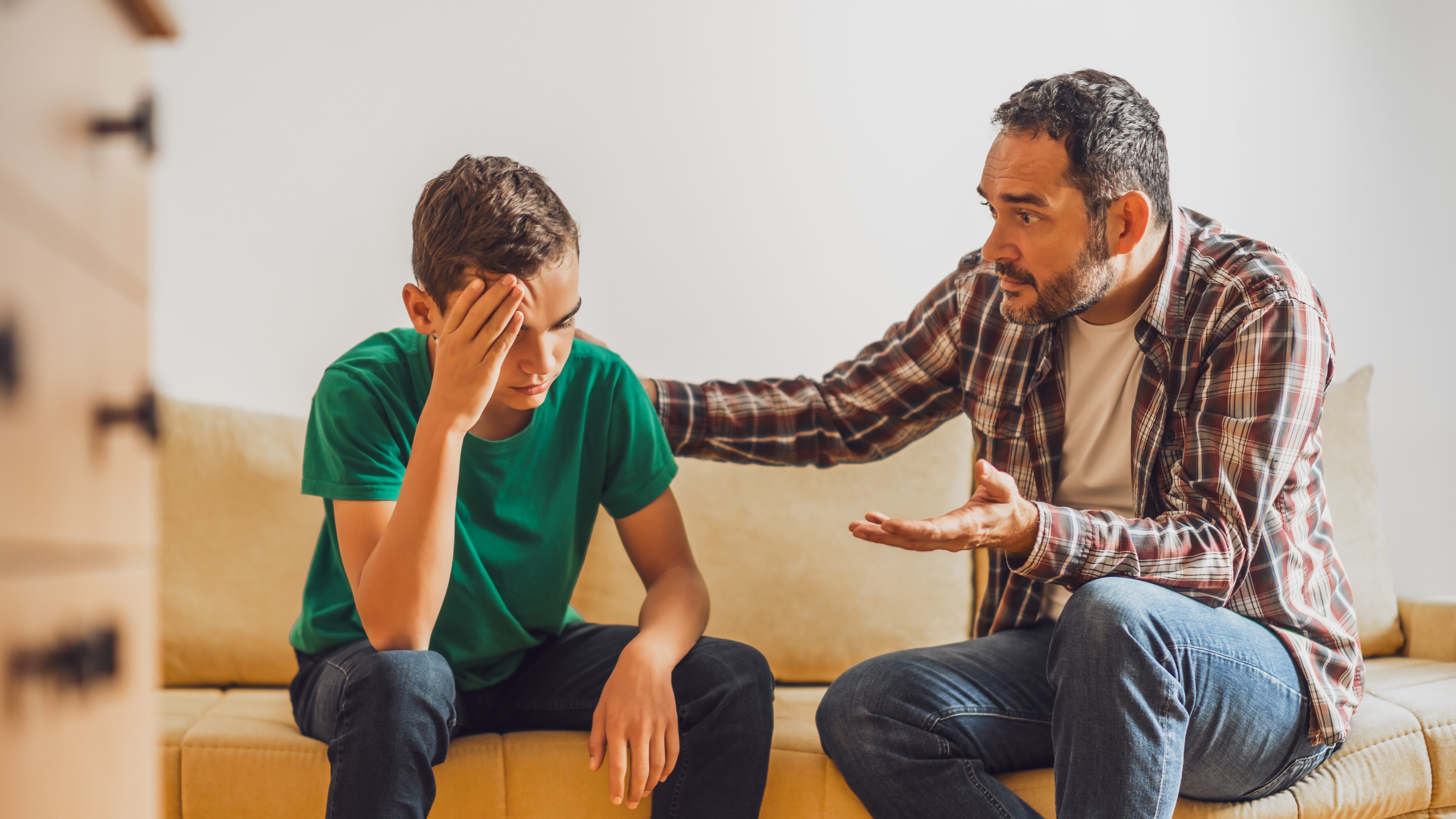 Father and son are talking at home. Son is having issues and father is consoling him.