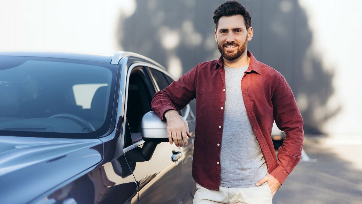Persona joven junto a su auto en ciudad, reflejando el momento de comprar tu primer auto