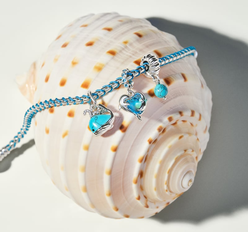 Azules profundos, turquesas brillantes y acentos coralinos que transforman charms, collares y brazaletes en piezas cargadas de historias, recuerdos y sueños de verano