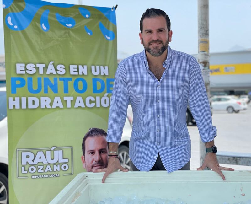 En García, el diputado Raúl Lozano está repartiendo bolsas con agua fresca.