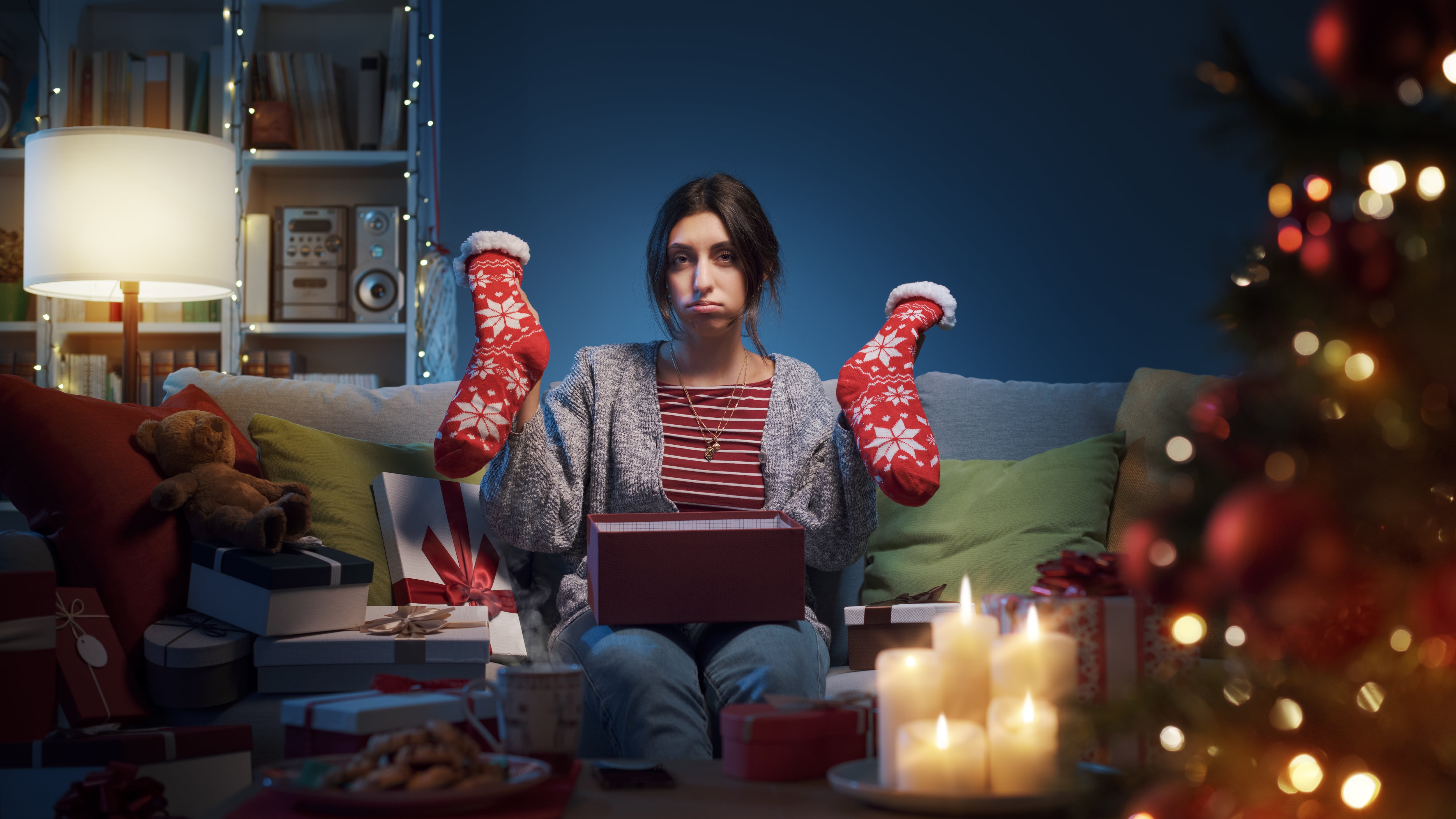 Mujer triste y decepcionada abriendo regalos de Navidad en casa, recibió calcetines de Navidad.