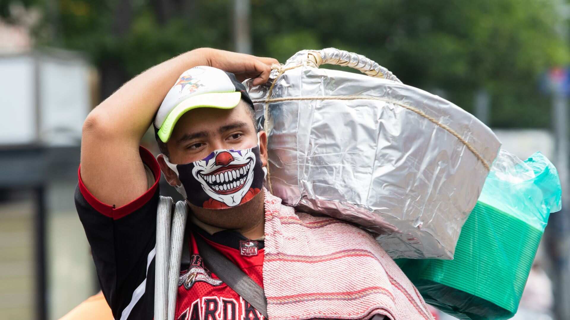 Un joven con cubrebocas de payaso vende tacos de canasta en la Merced.