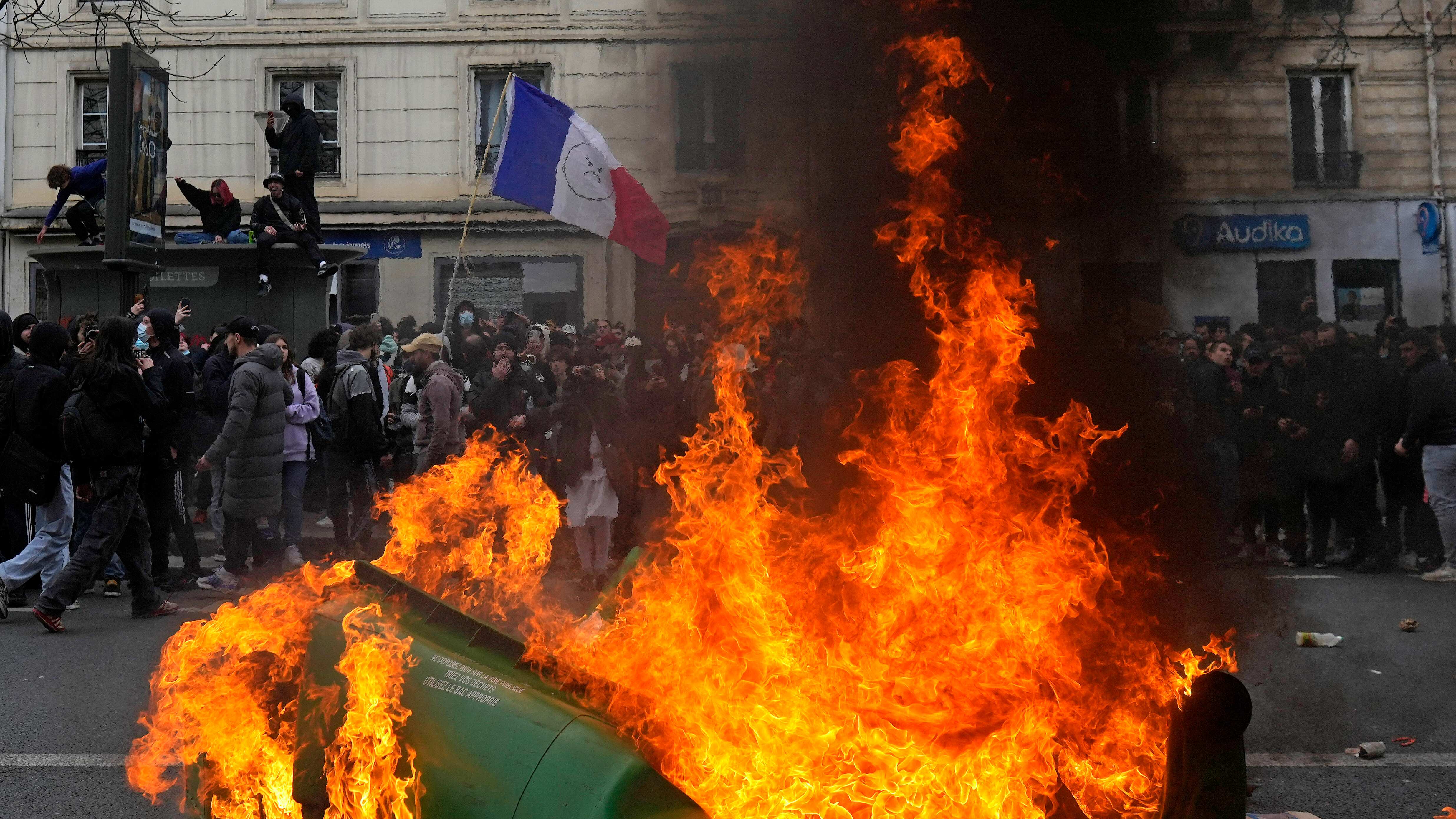Manifestantes pasan junto a varios contenedores de basura en llamas durante una protesta el martes 28 de marzo de 2023 en París. Es una nueva ronda de protestas y huelgas nacionales contra una impopular reforma de las pensiones. (AP Foto/Thibault Camus)