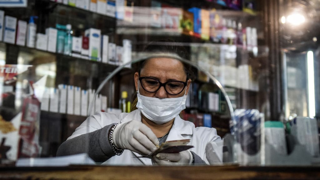 BUENOS AIRES, ARGENTINA - APRIL 08: Pharmacy cashier Silvia Carballo wearing a face mask and gloves counts bills at 'Farmacia de la Estrella' on April 08, 2020 in Buenos Aires, Argentina. 'Farmacia de la Estrella' is the first pharmacy of Buenos Aires city, founded in 1834 by Dr. Bernardino Rivadavia and still preserves its original decoration. President Alberto Fernandez informed that the lock down will be extended beyond April 12. Argentina was the first country in South America to order mandatory isolation, since March 20.