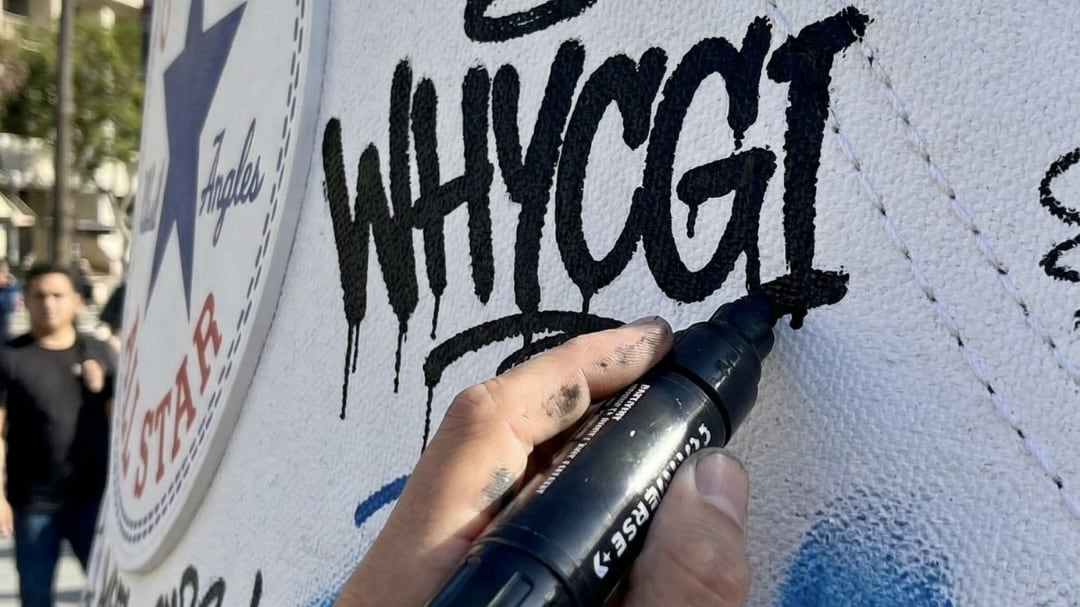 Una instalación artística transformó una pieza de calzado Converse en arte urbano cubierta de grafitis, mensajes y firmas, fusionando la cultura sneaker con el arte callejero. Foto: Why Agency.