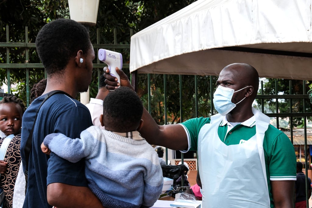 Un funcionario de salud utiliza un termómetro para examinar a las personas frente al Hospital Musulmán de Kibuli en Kampala, Uganda. (Foto AP/Hajarah Nalwadda)