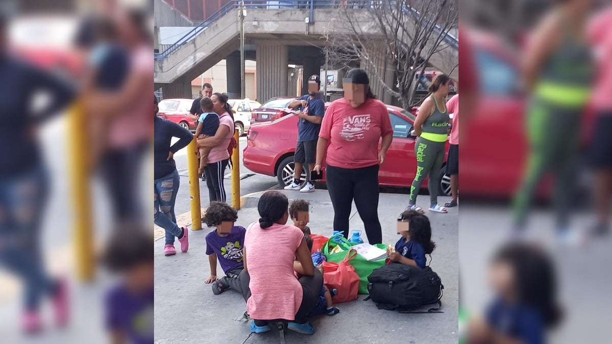 Algunas madres con sus hijos se acercan a la puerta del centro comercial porque sale aire frío.