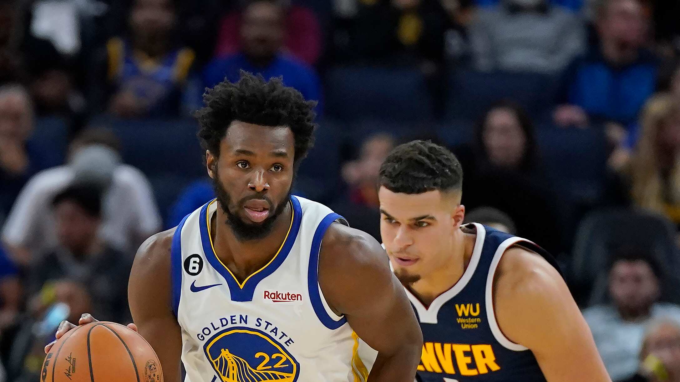 El alero de los Warriors de Golden State Andrew Wiggins avanza con el balón mientras lo persigue Michael Porter Jr. de los Nuggets de Denver en el encuentro de pretemporada el viernes 14 de octubre del 2022. (AP Foto/Jeff Chiu)