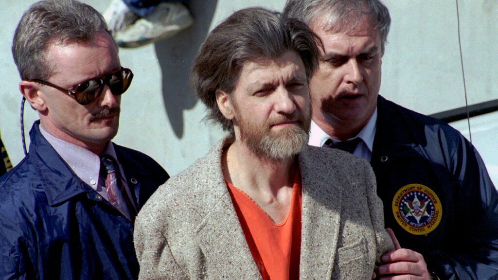 Theodore "Ted" Kaczynski es escoltado a su auto afuera de una corte federal en Helena, Montana, el 4 de abril de 1996.