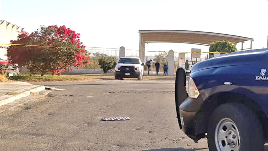 El cuerpo del agente quedó tirado en el estacionamiento en frente de la escuela.