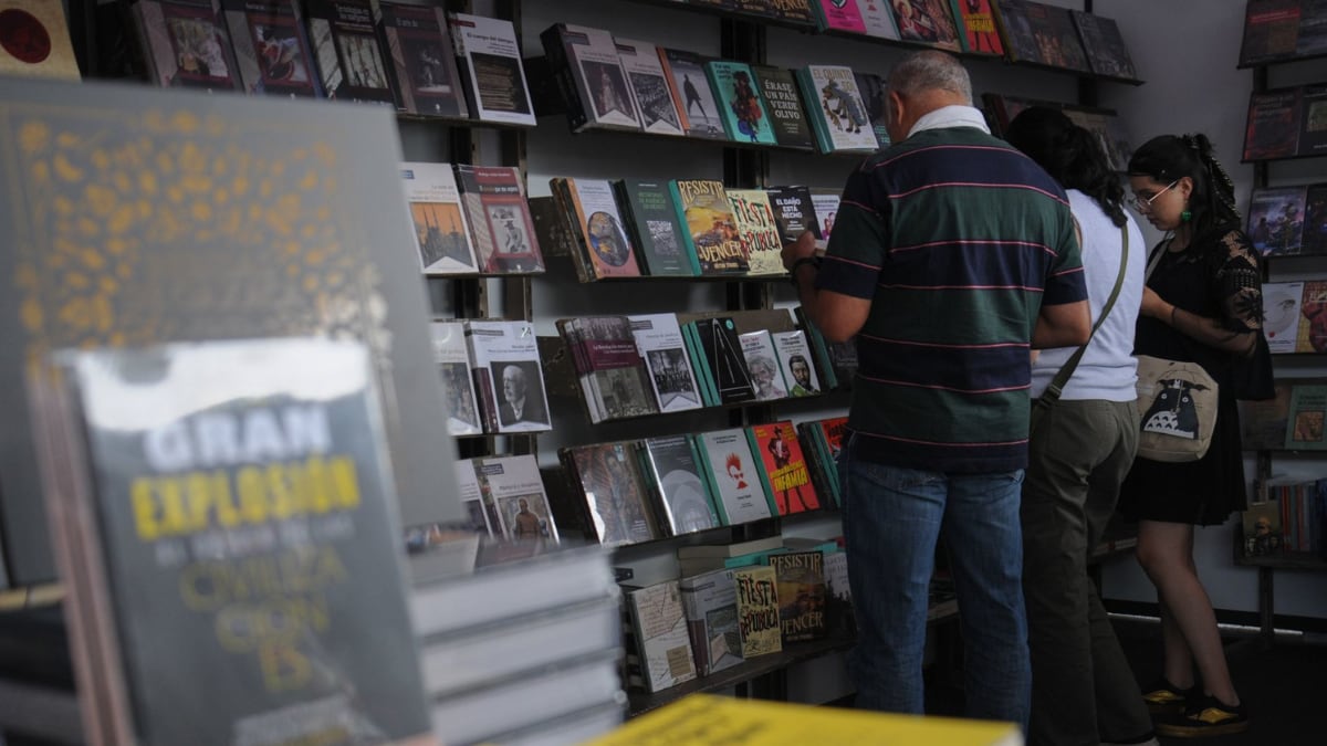 Unas personas leen y observan libros que se encuentran a la venta.